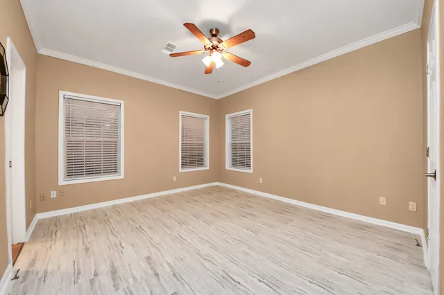 an empty room with wooden floor and windows