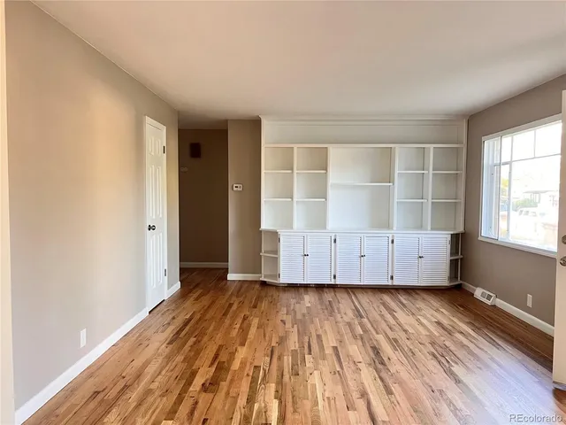 an empty room with wooden floor and windows