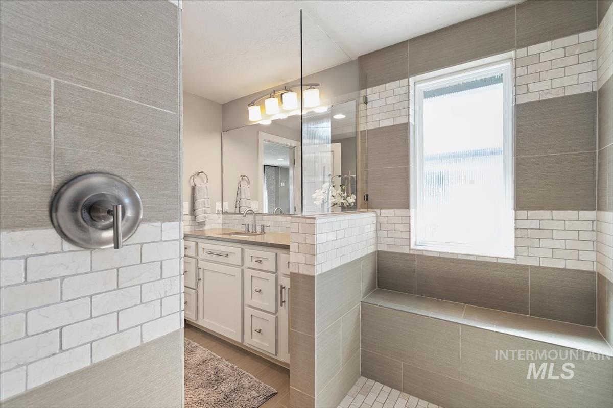 709 East Braemere Road Boise, ID 83702 - Photo 18 of 50 Neutral-toned tile shower with built-in bench seating, white subway tile accents, and a frosted window