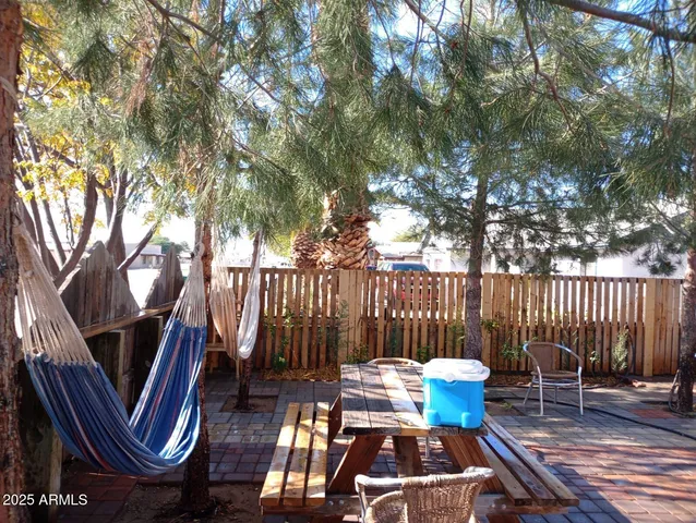 a view of backyard with table and chairs potted plants and wooden fence
