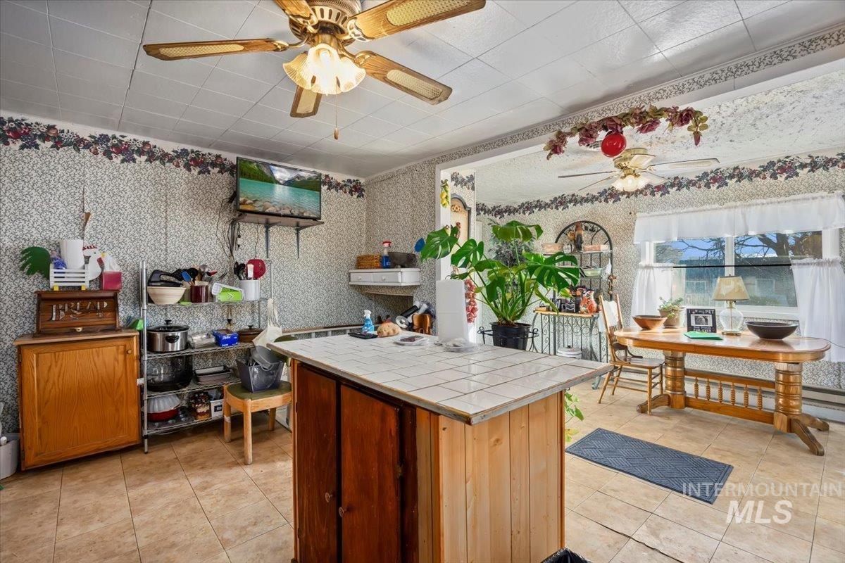 534 Miller Avenue Burley, ID 83318 - Photo 11 of 27 Kitchen featuring tile countertops, light tile patterned floors, ceiling fan, wallpapered walls, and a center island