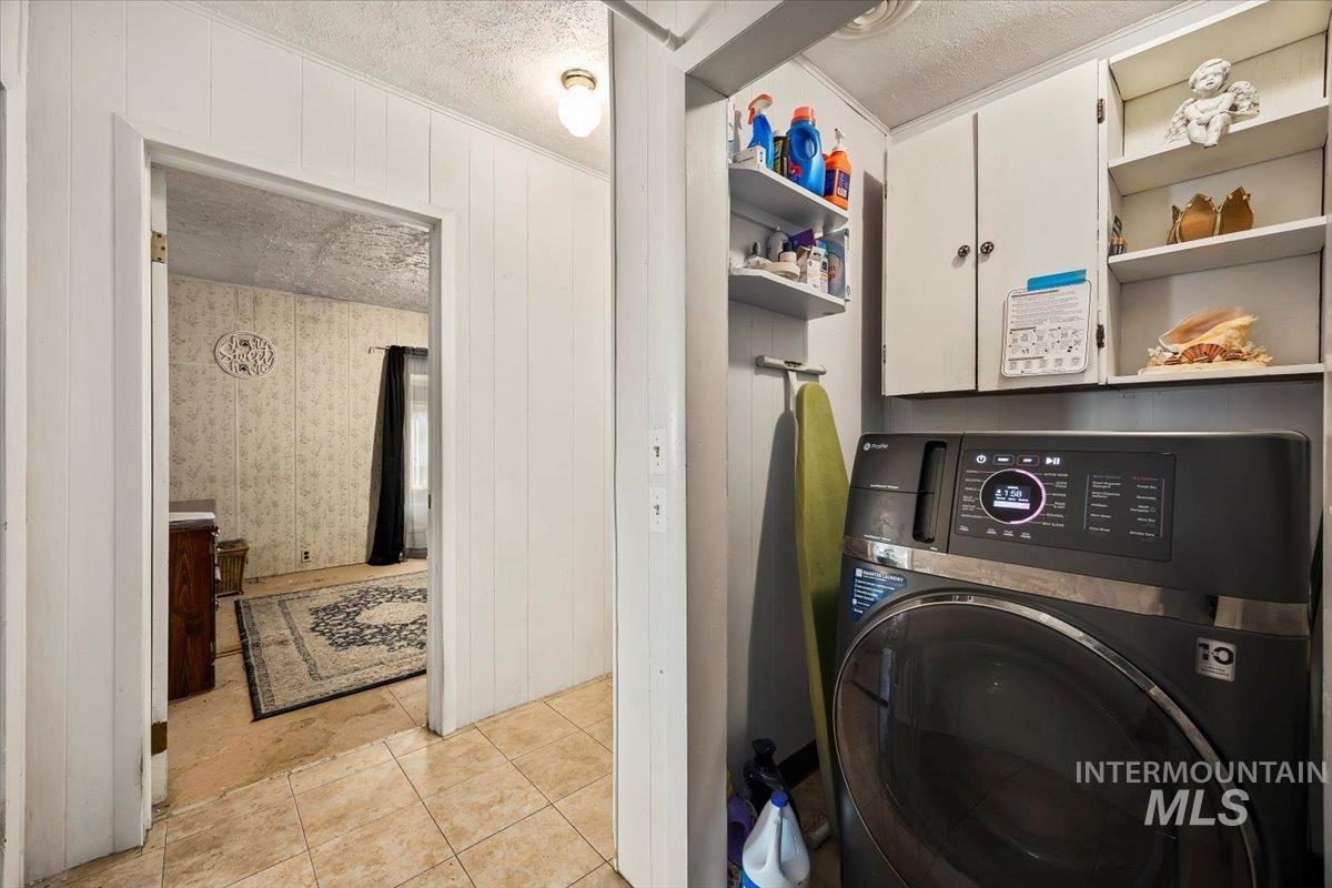 534 Miller Avenue Burley, ID 83318 - Photo 21 of 27 Laundry room with a textured ceiling, washer / dryer, light tile patterned flooring, and wood walls