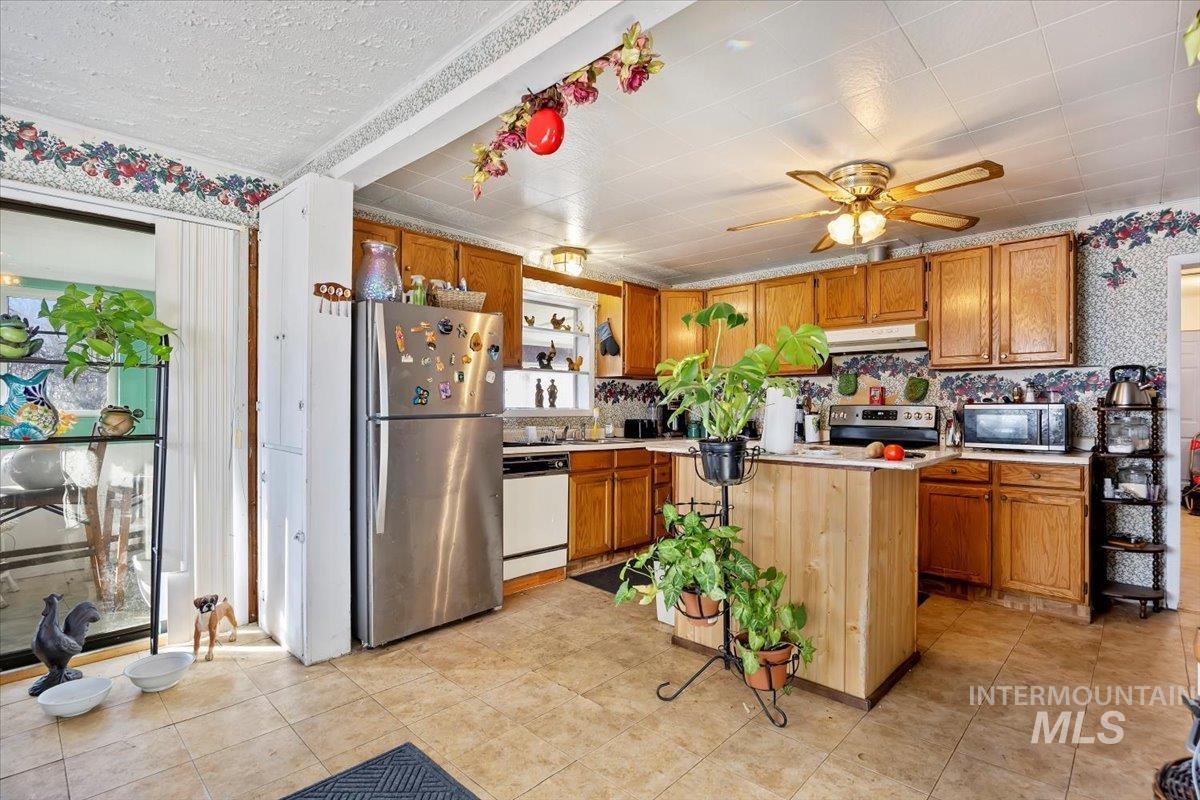 534 Miller Avenue Burley, ID 83318 - Photo 7 of 27 Kitchen with light countertops, stainless steel appliances, a ceiling fan, wood finish cabinetry, and wallpapered walls