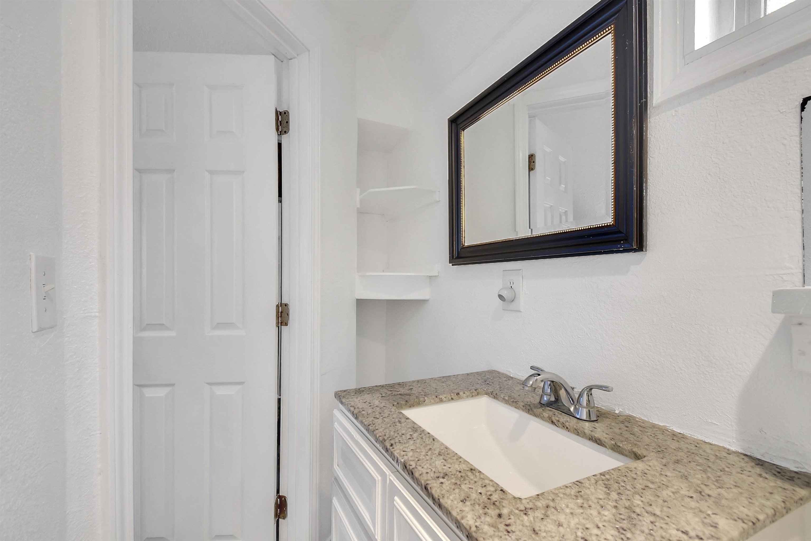 4895 Ave D, Unit B St. Augustine, FL 32095 - Photo 18 of 22 a bathroom with a granite countertop sink a mirror and vanity