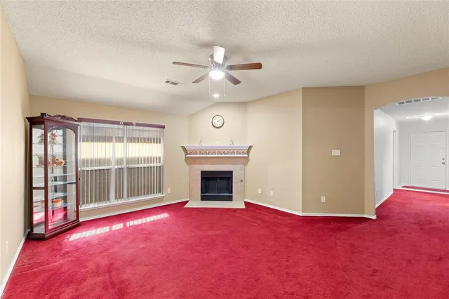 an empty room with fireplace fan and windows