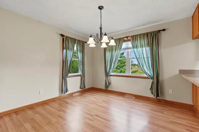 a kitchen with stainless steel appliances granite countertop a refrigerator a sink dishwasher a stove and white countertops with wooden floor