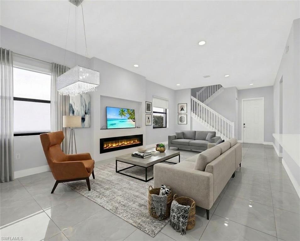 9045 Madrid Circle Naples, FL 34104 - Photo 11 of 46 Virtually Staged Open-concept living space featuring sleek tile flooring, a contemporary linear fireplace, and recessed lighting