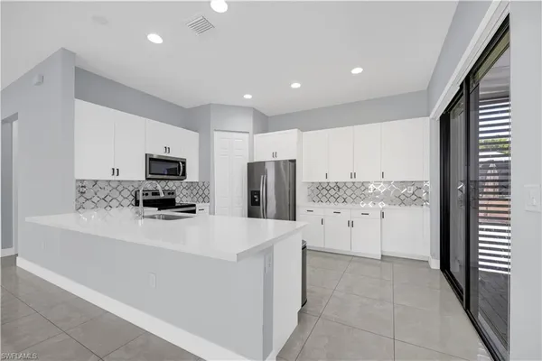 a kitchen with stainless steel appliances a refrigerator sink stove and white cabinets