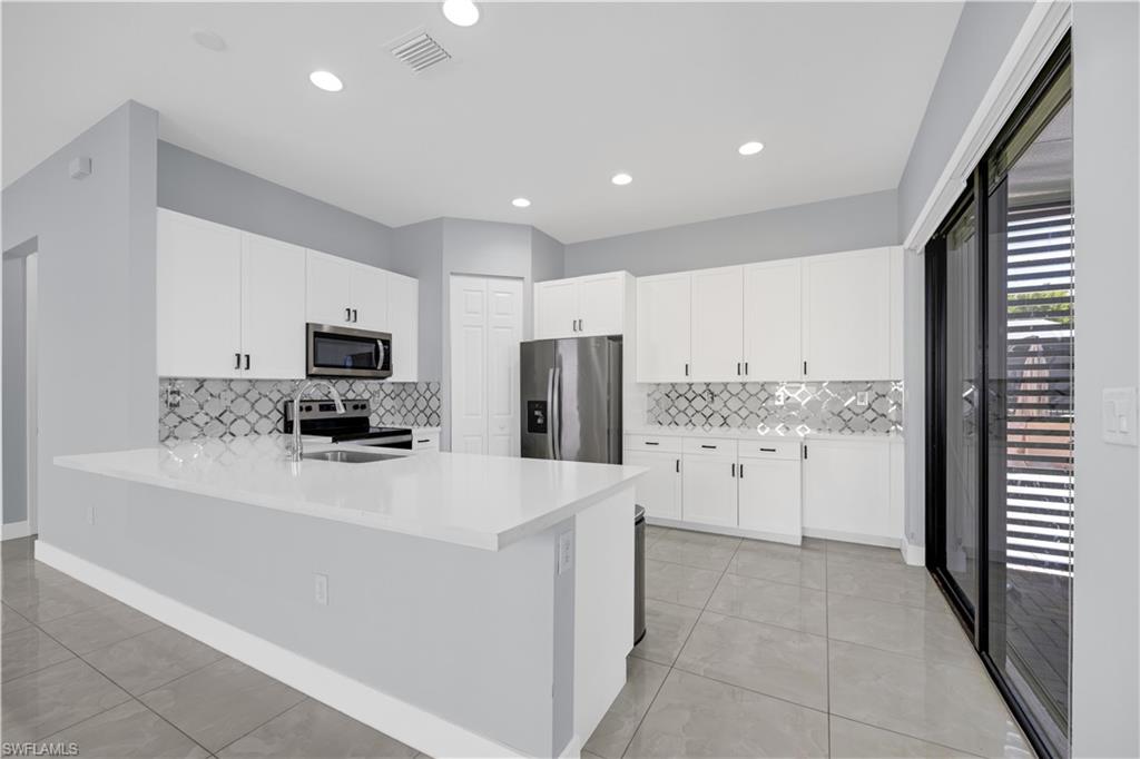 9045 Madrid Circle Naples, FL 34104 - Photo 16 of 46 a kitchen with stainless steel appliances a refrigerator sink stove and white cabinets