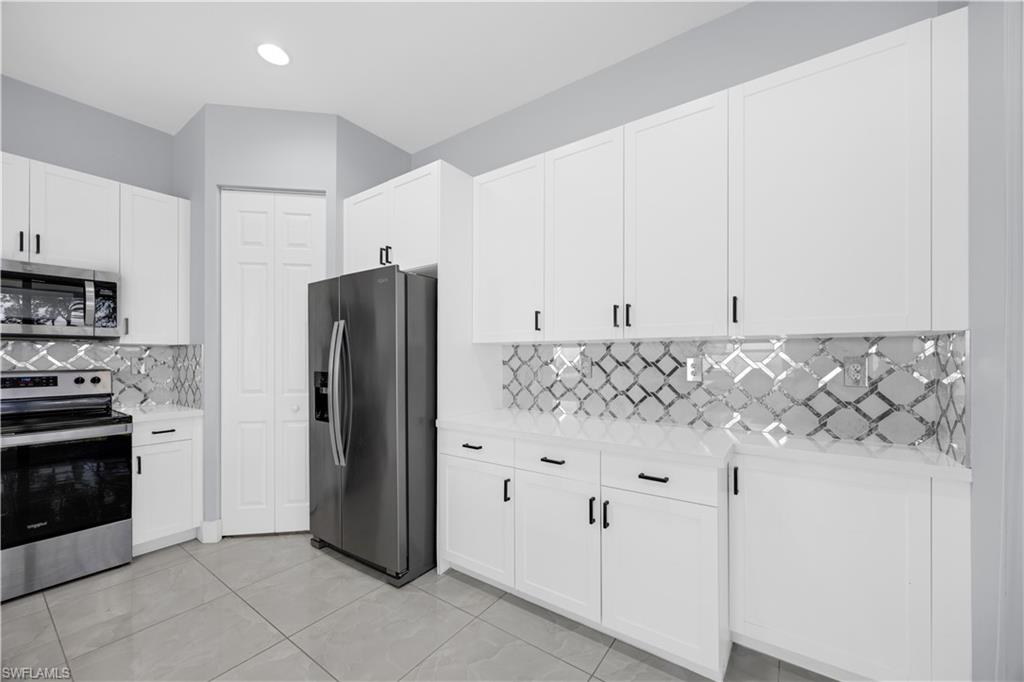 9045 Madrid Circle Naples, FL 34104 - Photo 17 of 46 a kitchen with stainless steel appliances granite countertop a refrigerator and a stove