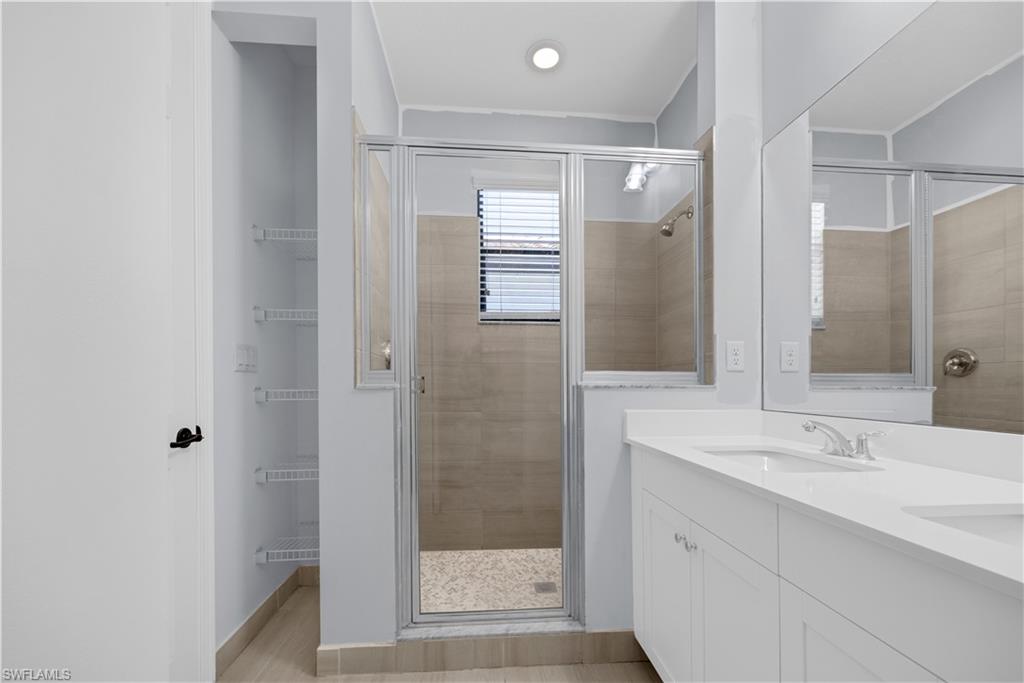 9045 Madrid Circle Naples, FL 34104 - Photo 33 of 46 a bathroom with a shower sink and mirror