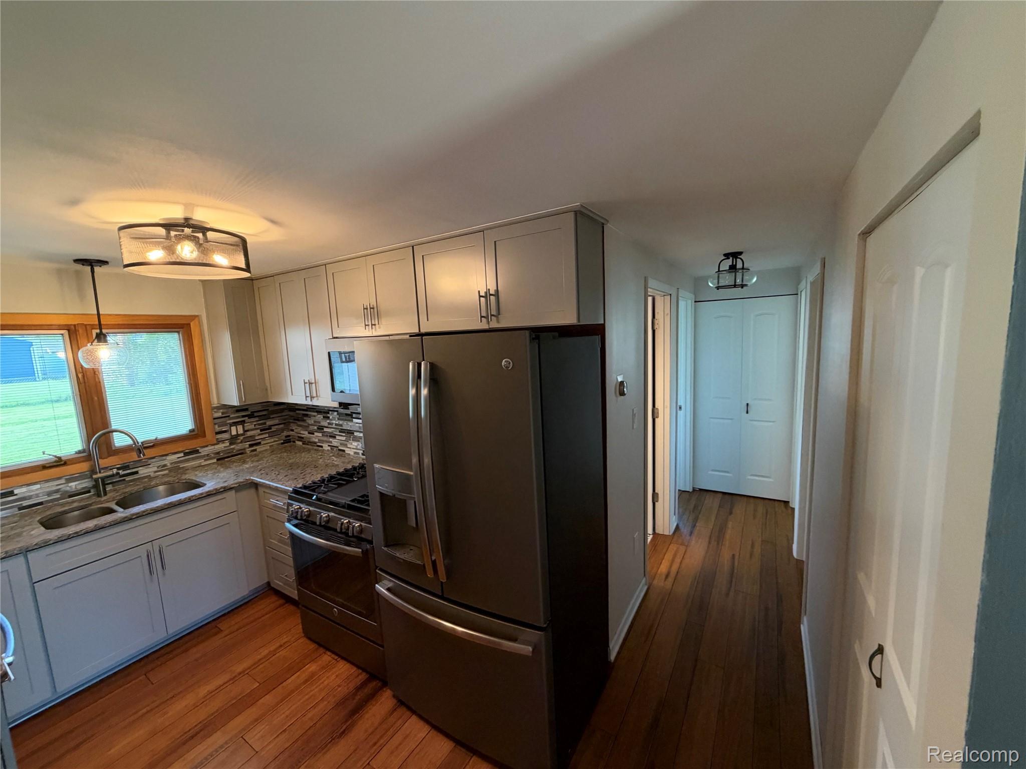 14629 Newburgh Road Livonia, MI 48154 - Photo 5 of 27 Modern kitchen featuring light cabinetry, dark stainless steel appliances, and a mosaic tile backsplash