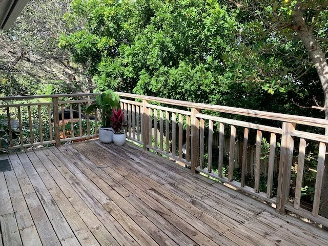 a balcony with wooden floor and trees in the back