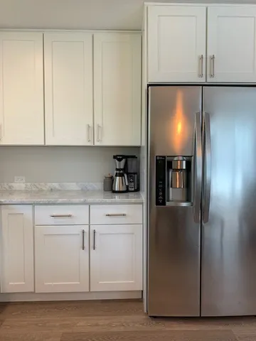 a kitchen with stainless steel appliances granite countertop a refrigerator a sink and white cabinets