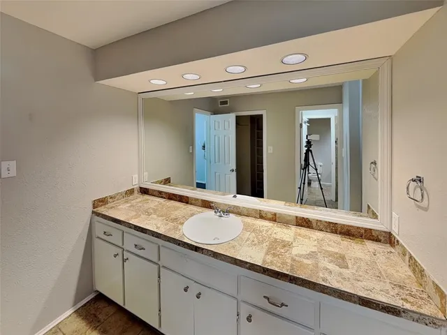 a bathroom with a granite countertop sink and a mirror