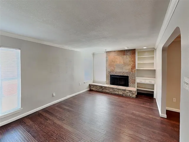 a view of an empty room with wooden floor fireplace and a window