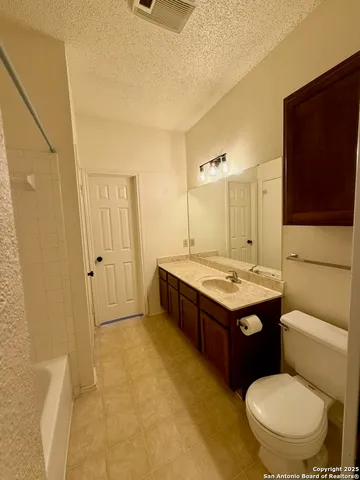 a bathroom with a granite countertop toilet sink and mirror