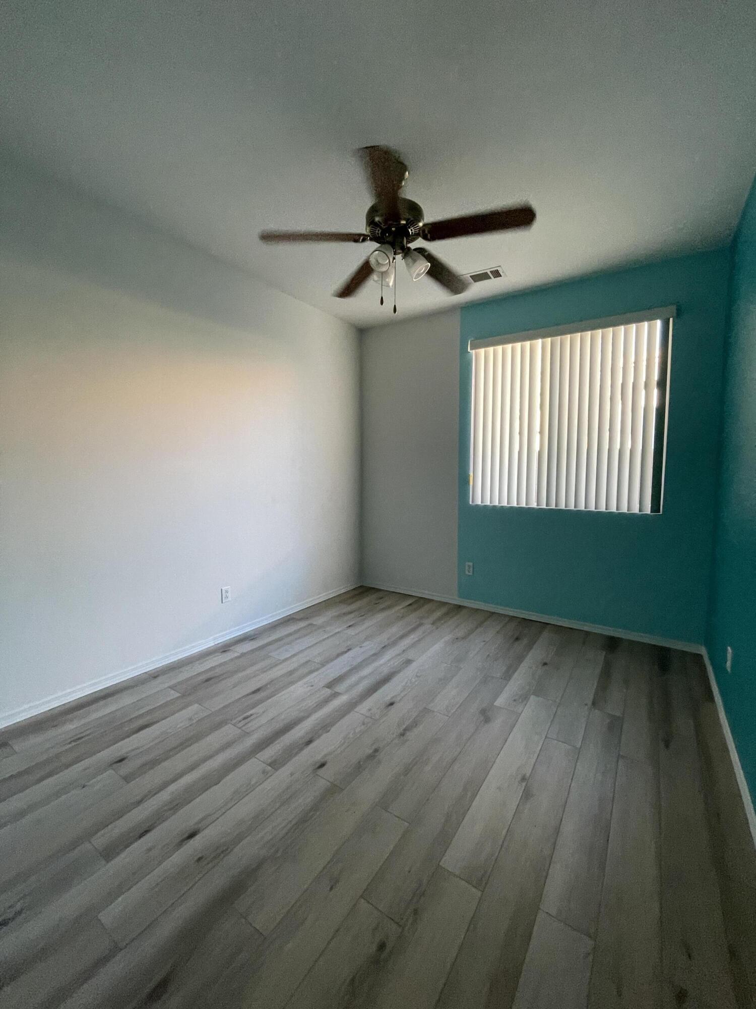 80733 Diamondback Trail Indio, CA 92201 - Photo 12 of 16 an empty room with wooden floor fan and windows