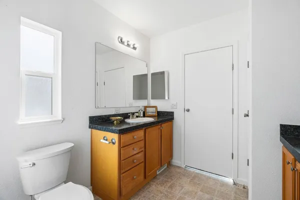 a bathroom with a granite countertop toilet sink and mirror
