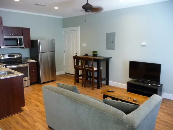 a living room with furniture a flat screen tv and kitchen view