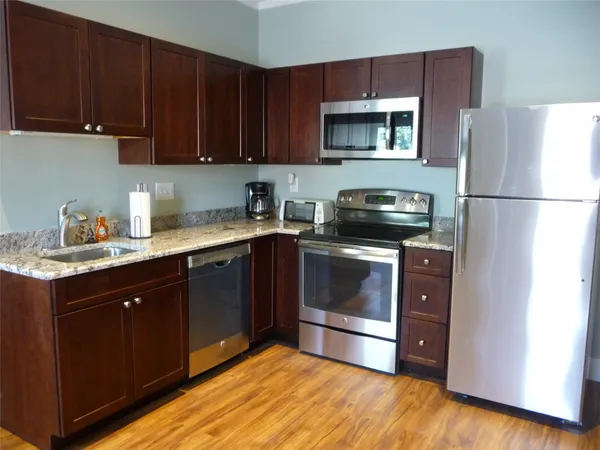 a kitchen with stainless steel appliances granite countertop a refrigerator a stove a sink and a microwave