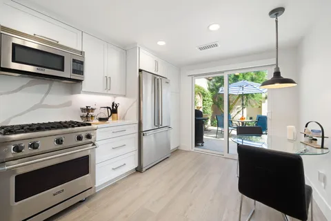 a kitchen with stainless steel appliances white cabinets a stove a sink and a refrigerator