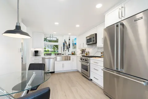 a kitchen with white cabinets and stainless steel appliances
