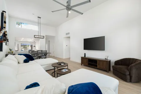 a living room with furniture a flat screen tv and kitchen view