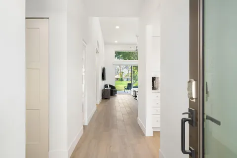 a view of a hallway with a livingroom and a hall with wooden floor