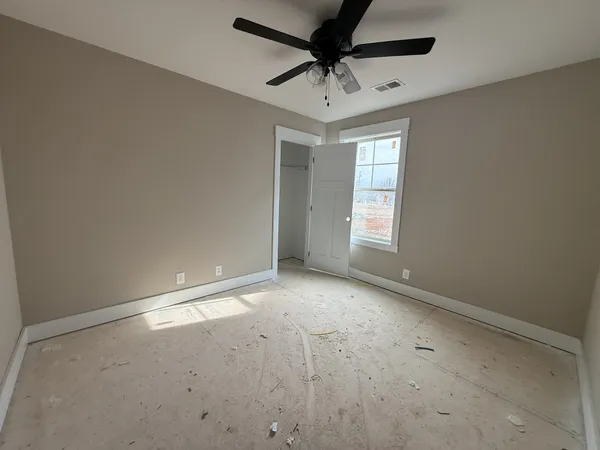 an empty room with windows and fan