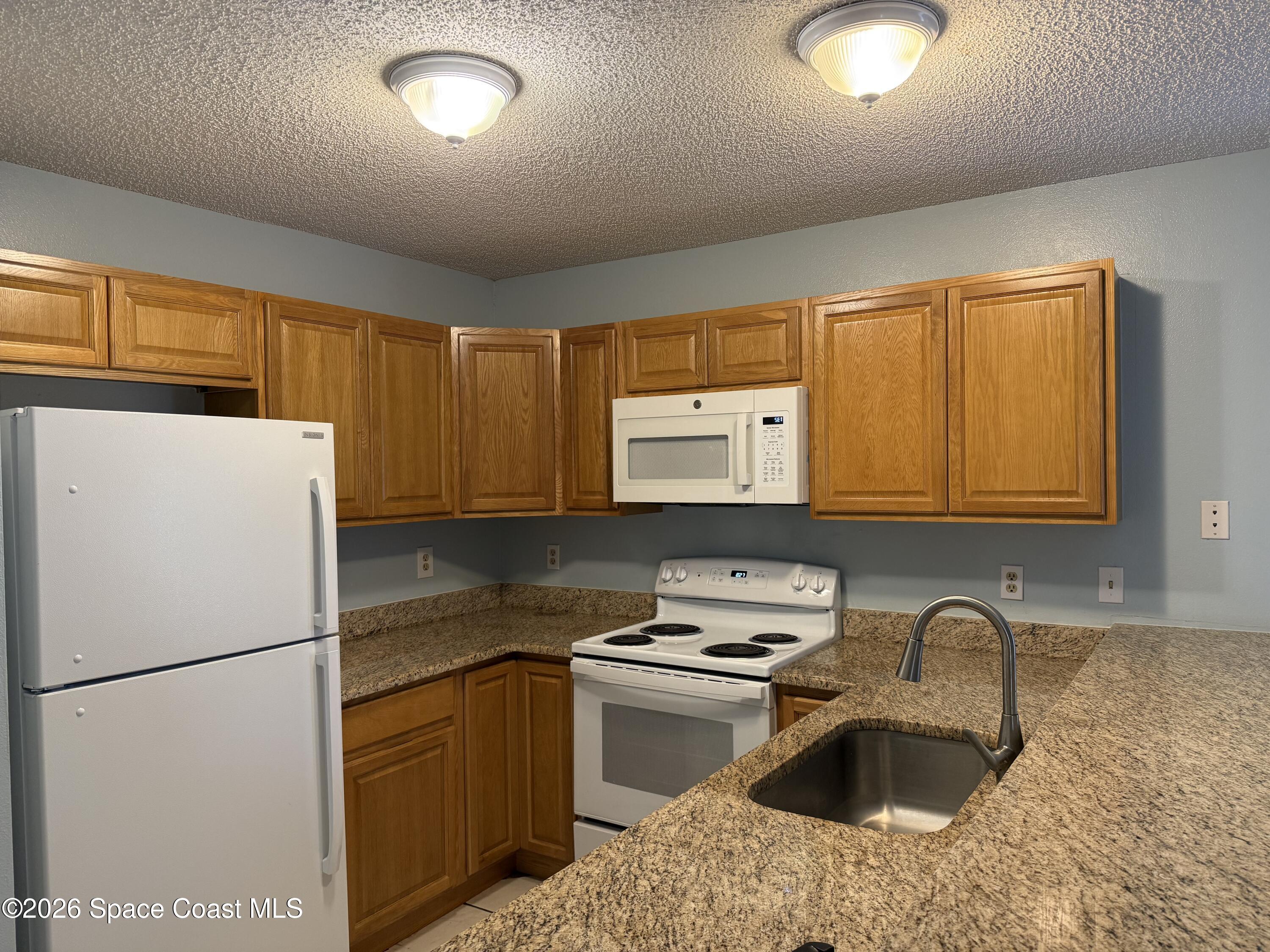 1461 Sheafe Avenue Northeast, Unit 106 Palm Bay, FL 32905 - Photo 4 of 13 a kitchen with a refrigerator sink and stove