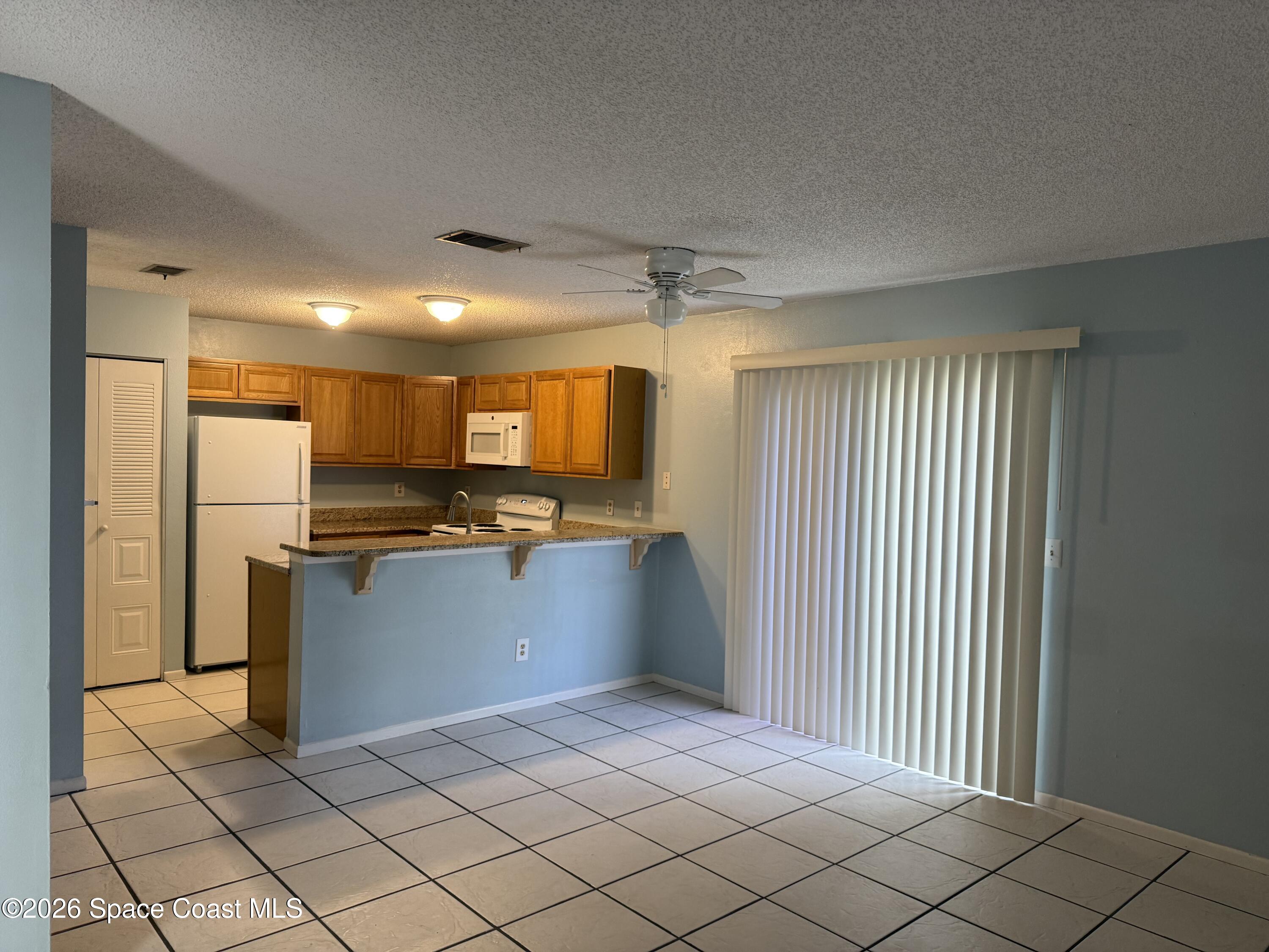 1461 Sheafe Avenue Northeast, Unit 106 Palm Bay, FL 32905 - Photo 5 of 13 a kitchen with stainless steel appliances kitchen island granite countertop a refrigerator and a sink