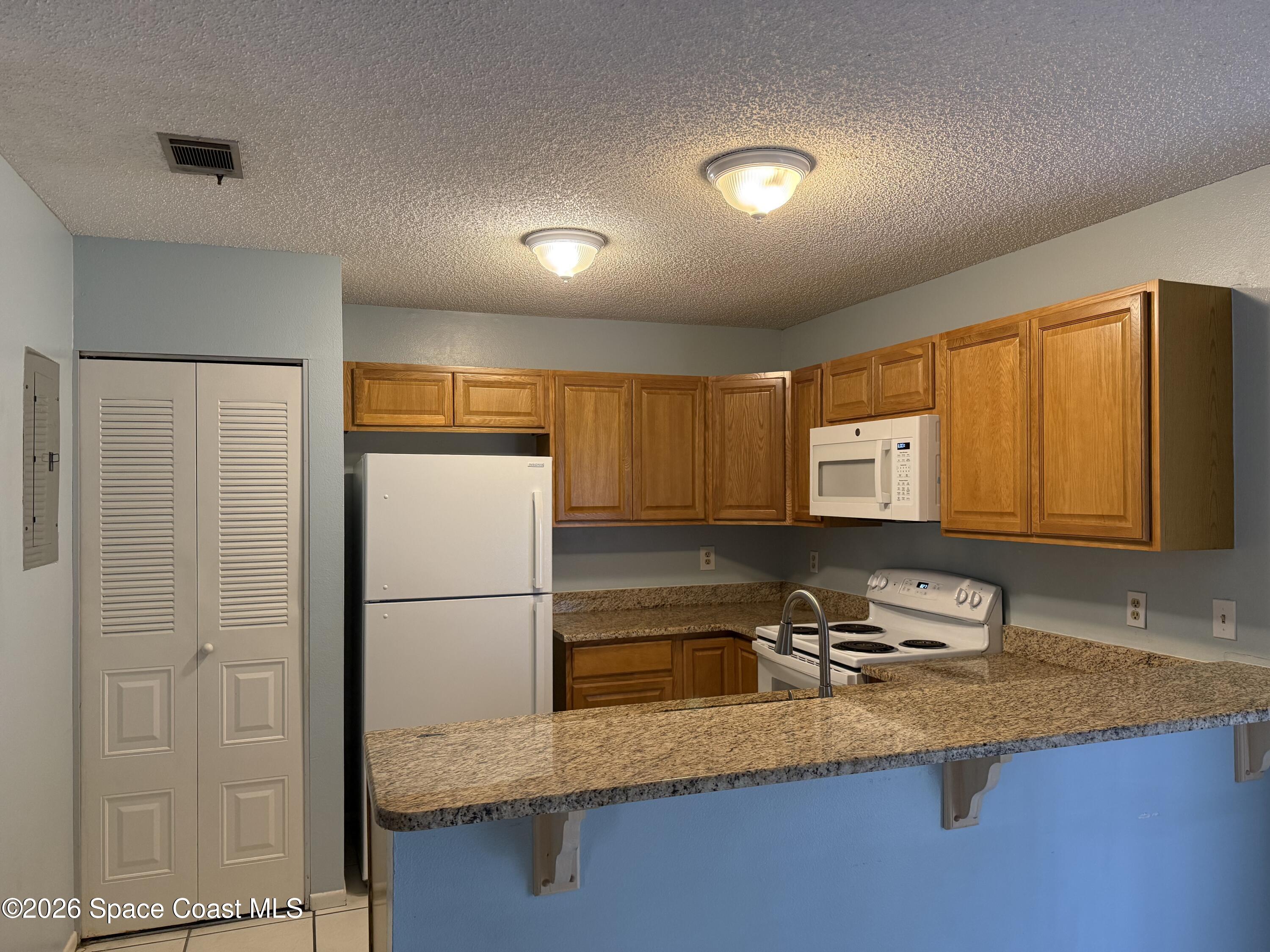 1461 Sheafe Avenue Northeast, Unit 106 Palm Bay, FL 32905 - Photo 6 of 13 a kitchen with stainless steel appliances granite countertop a sink refrigerator and cabinets
