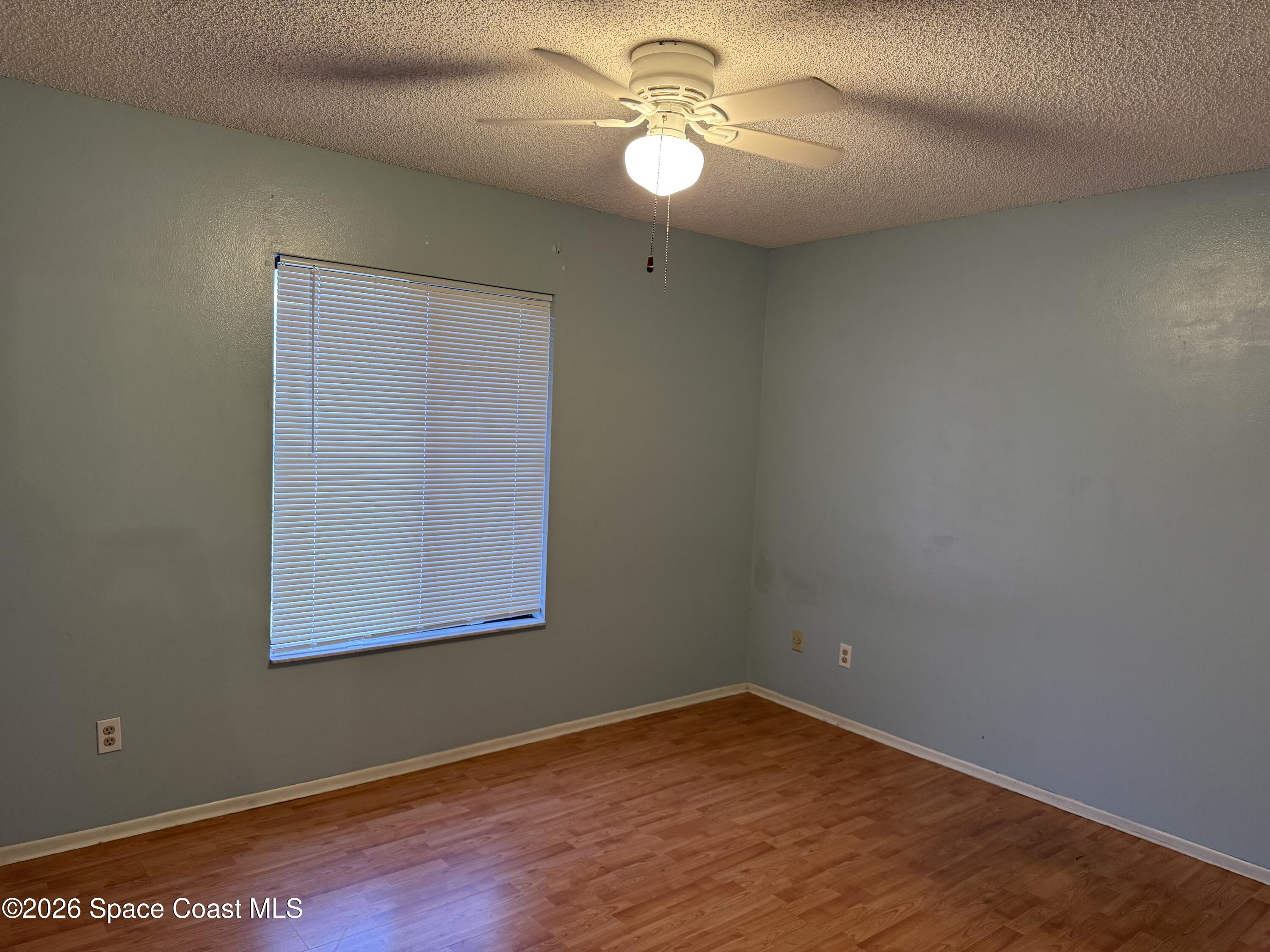 1461 Sheafe Avenue Northeast, Unit 106 Palm Bay, FL 32905 - Photo 9 of 13 an empty room with wooden floor chandelier fan and windows