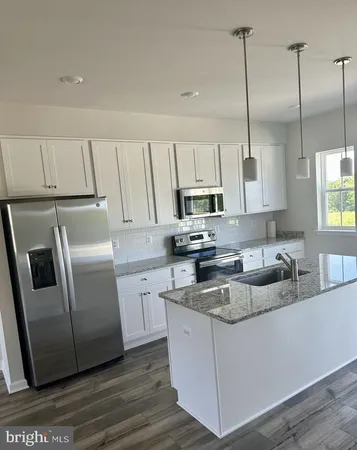 a kitchen with stainless steel appliances granite countertop a refrigerator a sink a stove a microwave and wooden floors