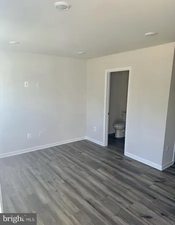 a view of an empty room with wooden floor and closet