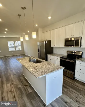 a kitchen with stainless steel appliances kitchen island granite countertop a stove a sink and a microwave