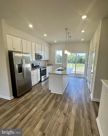 a kitchen with kitchen island wooden floors appliances and cabinets