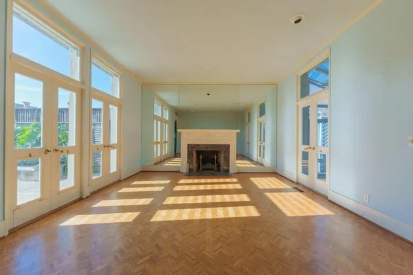 a view of an empty room with wooden floor and a fireplace