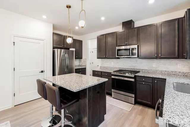 a kitchen with stainless steel appliances granite countertop a refrigerator a stove a sink a microwave and island