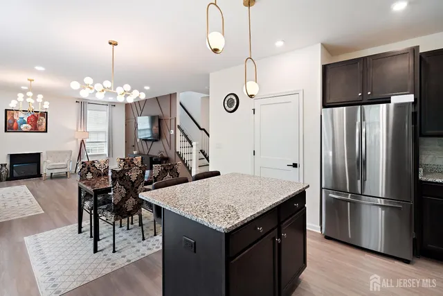 a kitchen with stainless steel appliances granite countertop a refrigerator a stove a sink dishwasher a dining table and chairs with wooden floor