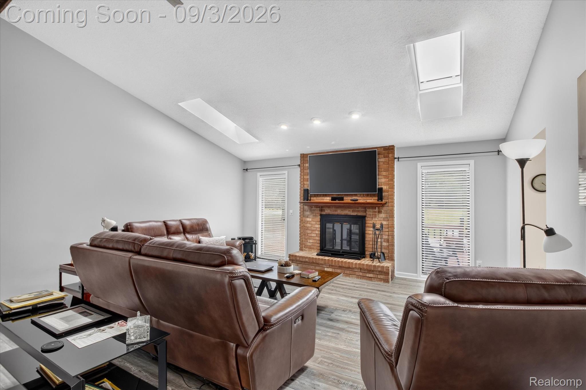 27260 Campbell Road Warren, MI 48093 - Photo 6 of 60 Vaulted ceiling with skylights, recessed lighting, brick fireplace, wood-finish flooring, and white window blinds