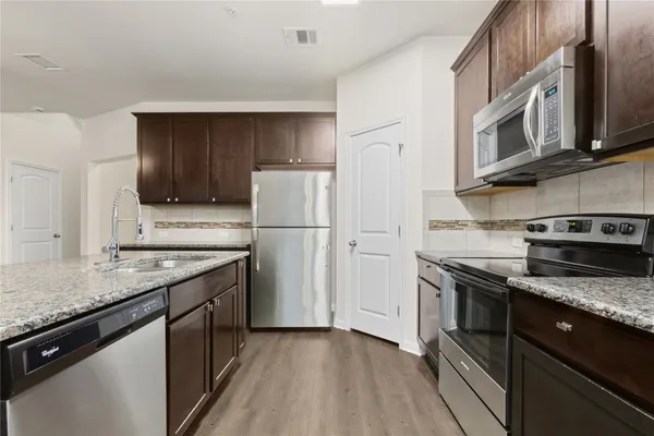 a kitchen with stainless steel appliances granite countertop a refrigerator a stove a sink and a microwave