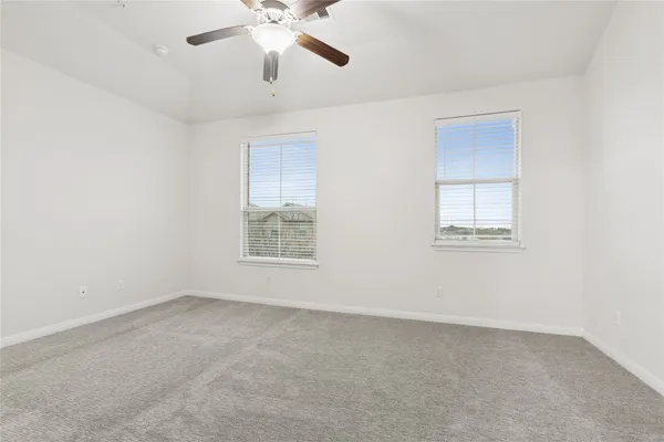an empty room with windows and fan
