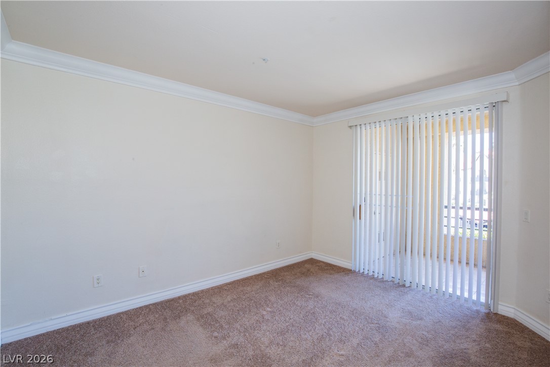 230 East Flamingo Road, Unit 122 Las Vegas, NV 89169 - Photo 6 of 7 A spacious room offers ample natural light and direct outdoor access through sliding doors.