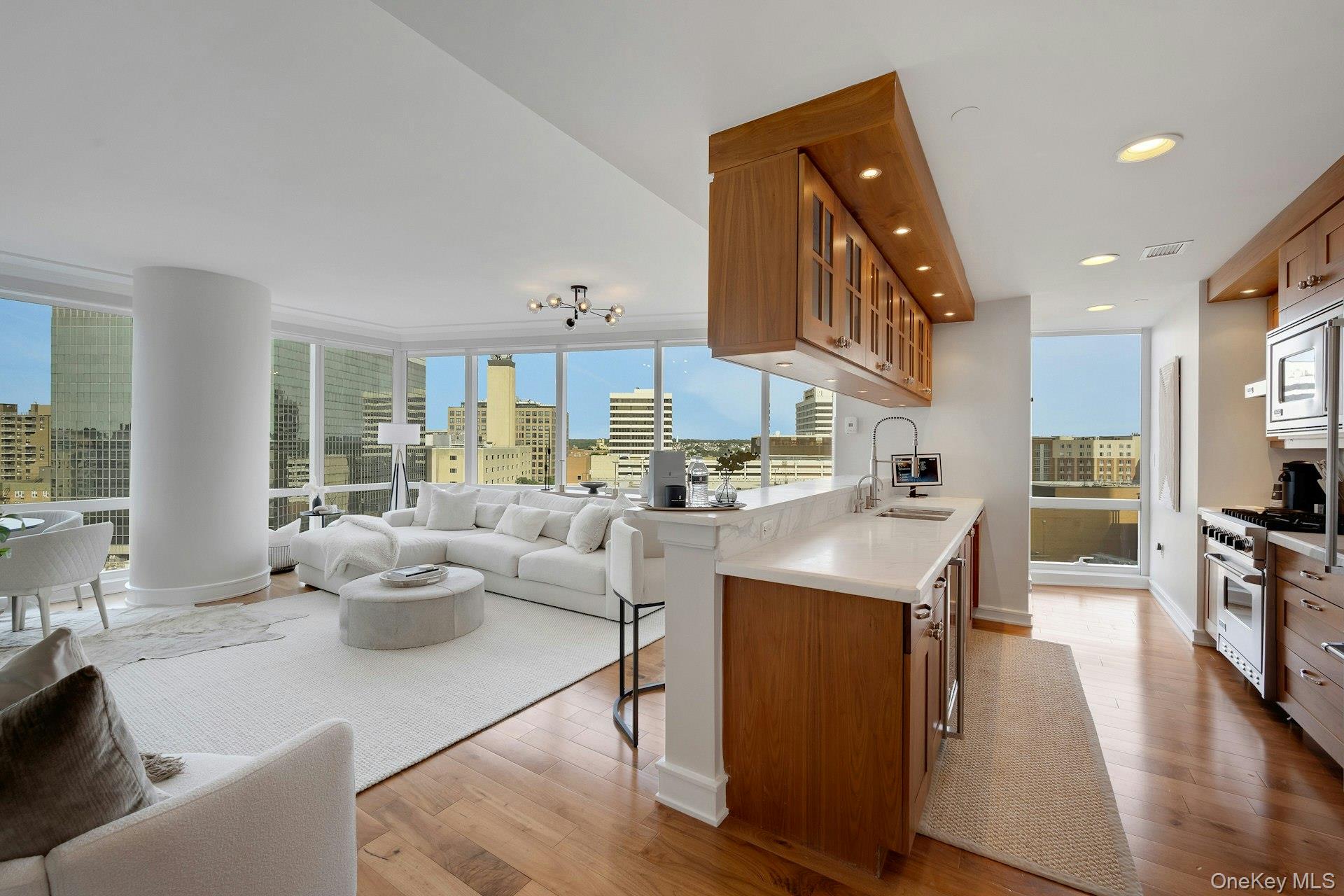 5 Renaissance Square, Unit 12A White Plains, NY 10601 - Photo 10 of 36 a living room with stainless steel appliances kitchen island granite countertop a table chairs and a view of kitchen