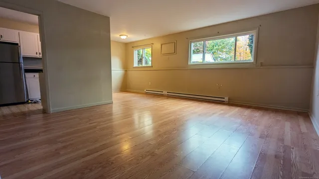 an empty room with wooden floor and windows