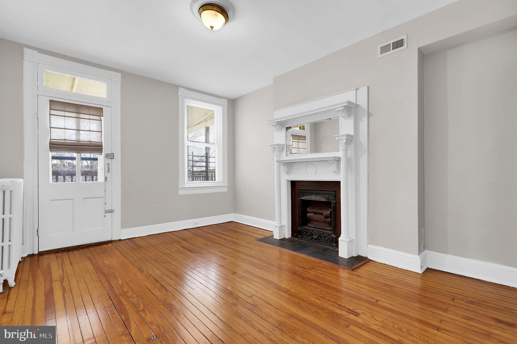 2511 North Calvert Street Baltimore, MD 21218 - Photo 14 of 37 an empty room with wooden floor fireplace and windows