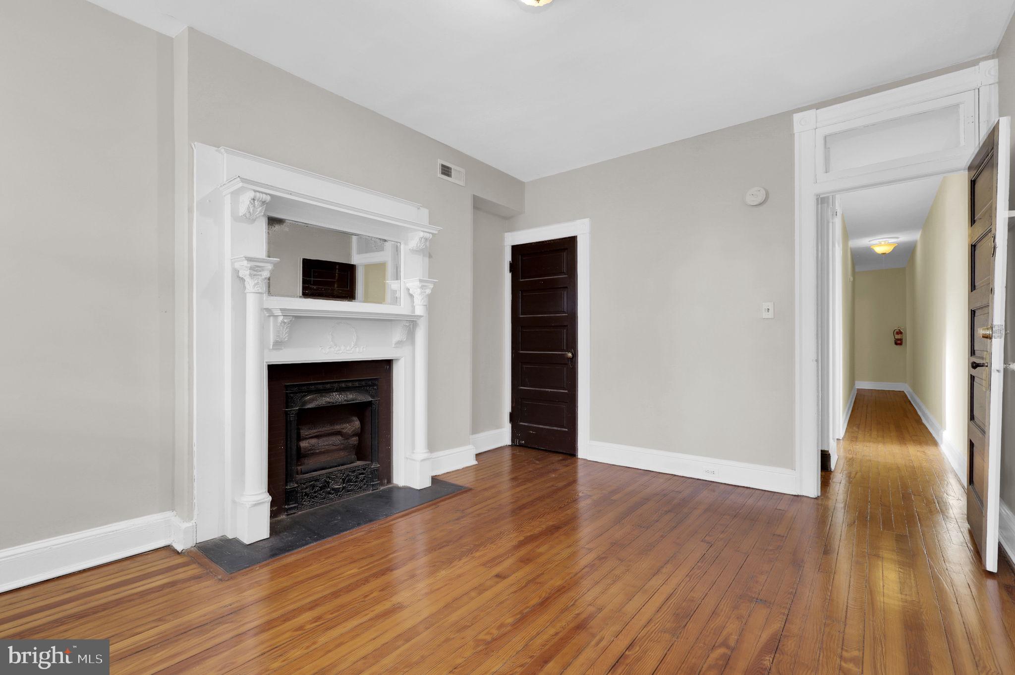 2511 North Calvert Street Baltimore, MD 21218 - Photo 15 of 37 a view of an empty room with wooden floor fireplace and a window