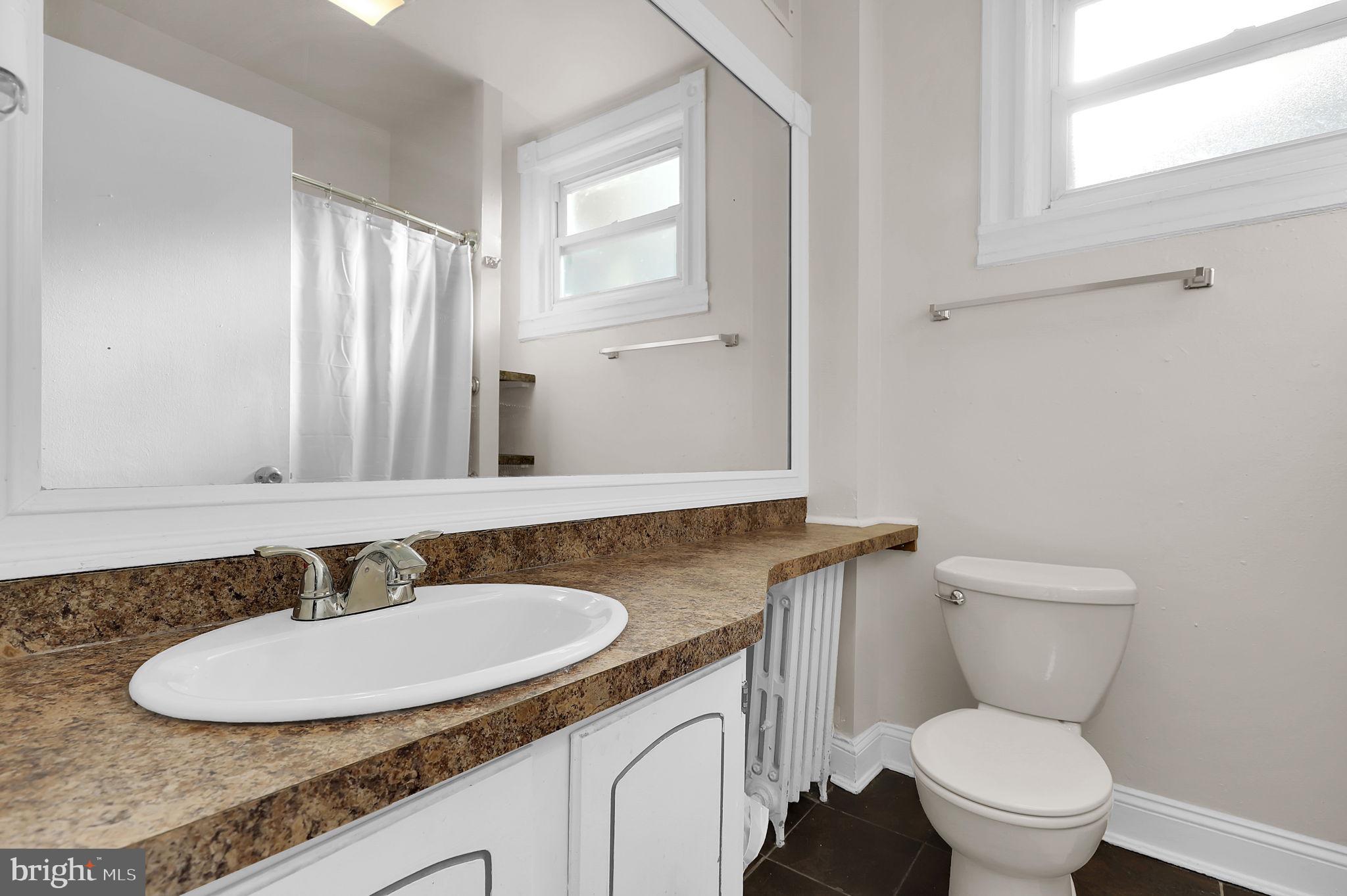 2511 North Calvert Street Baltimore, MD 21218 - Photo 17 of 37 a bathroom with a granite countertop sink and a mirror